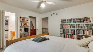 A bedroom with a large bed, a ceiling fan, a bookshelf, and a door leading to another room. - 9 Mi to Lake Keowee! Secluded Creekfront Getaway (Sunset)