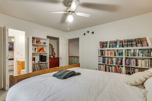 A bedroom with a large bed, a ceiling fan, a bookshelf, and a door leading to another room. - 9 Mi to Lake Keowee! Secluded Creekfront Getaway (Sunset)