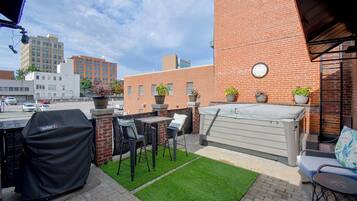 An outdoor patio with a barbecue grill, seating area, and potted plants.