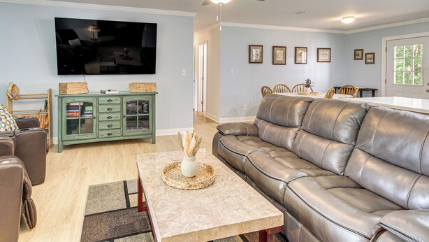 A living room with a leather sofa, a television, a cabinet, and a ceiling fan. - Family Getaway w/ Pool on 8 Acres in Carriere! (Carriere)