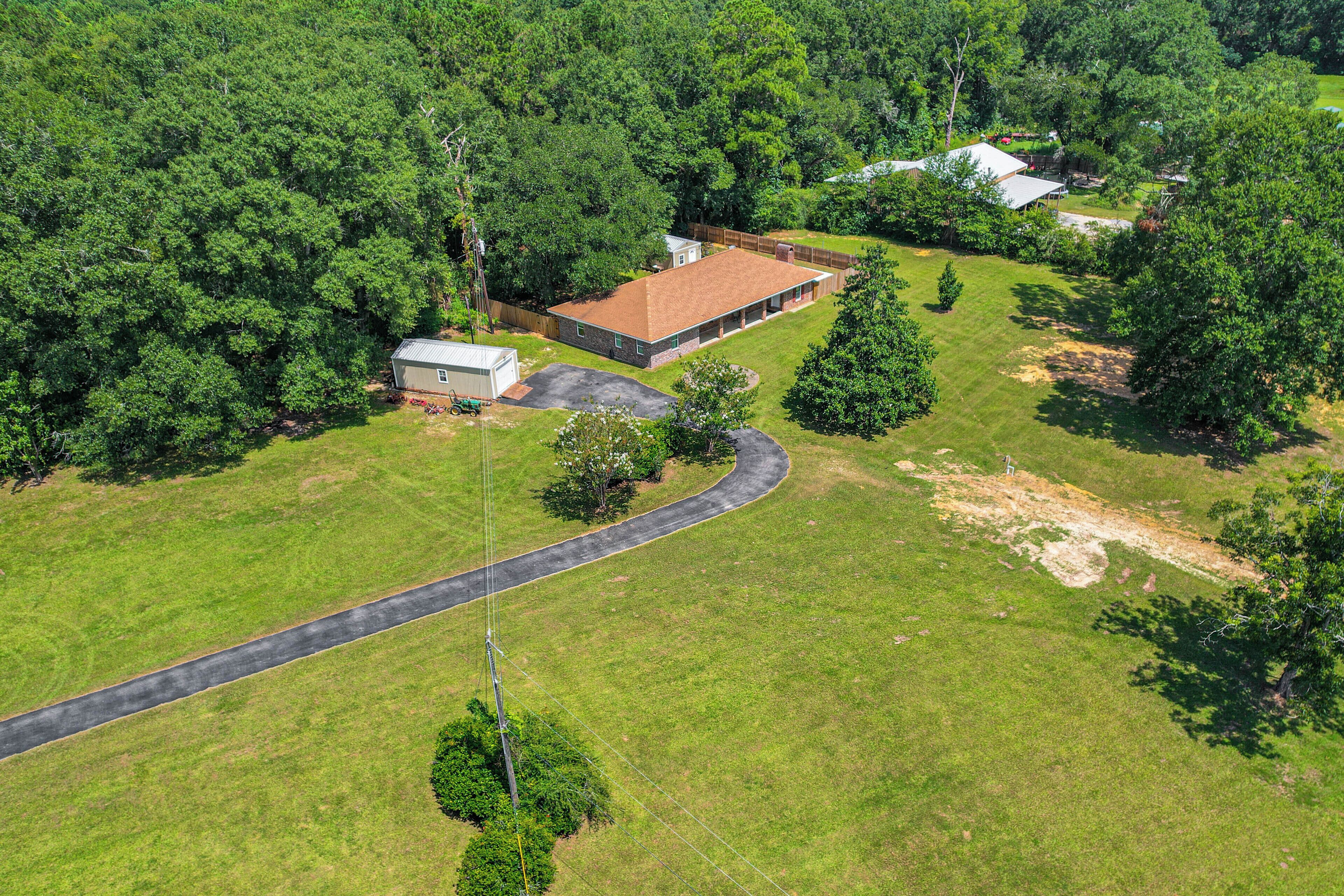 An aerial view of a residential property with a large house, a smaller shed, and a winding driveway.