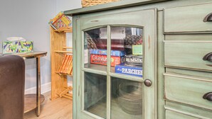 A vintage-style cabinet with glass doors, a small wooden table with a colorful book, and a chair. - Family Getaway w/ Pool on 8 Acres in Carriere! (Carriere)