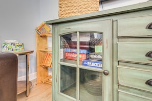 A vintage-style cabinet with glass doors, a small wooden table with a colorful book, and a chair. - Family Getaway w/ Pool on 8 Acres in Carriere! (Carriere)