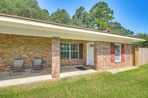 A single-story brick house with a covered porch, a front door, and a window. - Family Getaway w/ Pool on 8 Acres in Carriere! (Carriere)