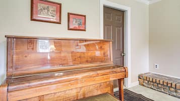 Un piano en bois se trouve dans une pièce dotée d’une porte et de deux tableaux encadrés accrochés au mur.