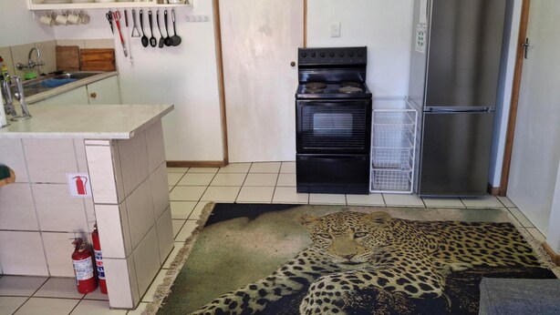 Una cocina equipada con estufa, horno, refrigerador y extintor.