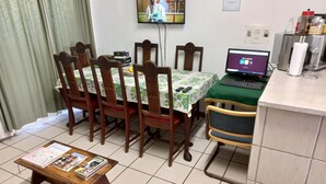 Un comedor con una mesa, sillas, una computadora portátil y un televisor.