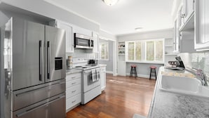 A modern kitchen with stainless steel appliances, a white backsplash, and a window with blinds. - Private Pool & Basketball Spacious 3BR Sleeps 9 (Wenatchee)