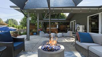 An outdoor patio area with a fire pit, outdoor furniture, and a covered seating area.