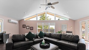 A spacious living room with a sectional sofa, a ceiling fan, and a large window providing natural light. - Private Pool & Basketball Spacious 3BR Sleeps 9 (Wenatchee)