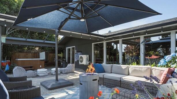 An outdoor patio with a fire pit, seating area, and a covered section with a large umbrella. - Private Pool & Basketball Spacious 3BR Sleeps 9 (Wenatchee)
