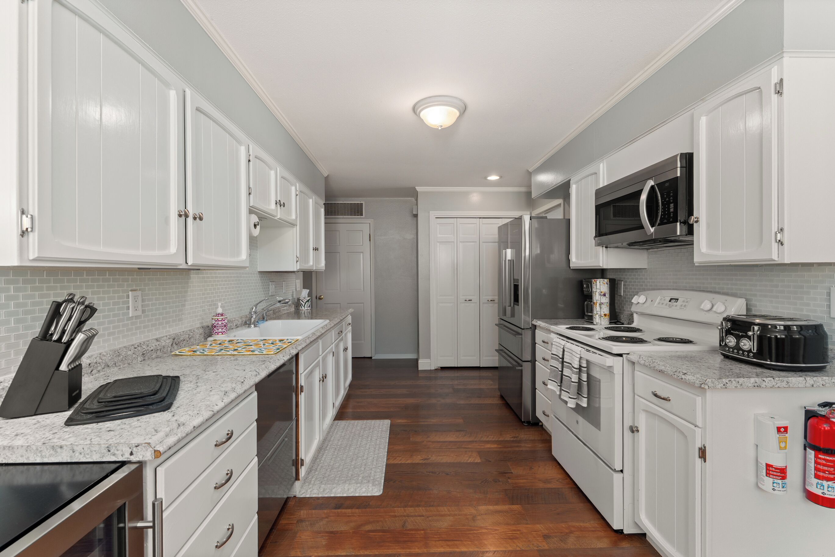 A kitchen with white cabinets, a microwave, a stove, and a toaster.