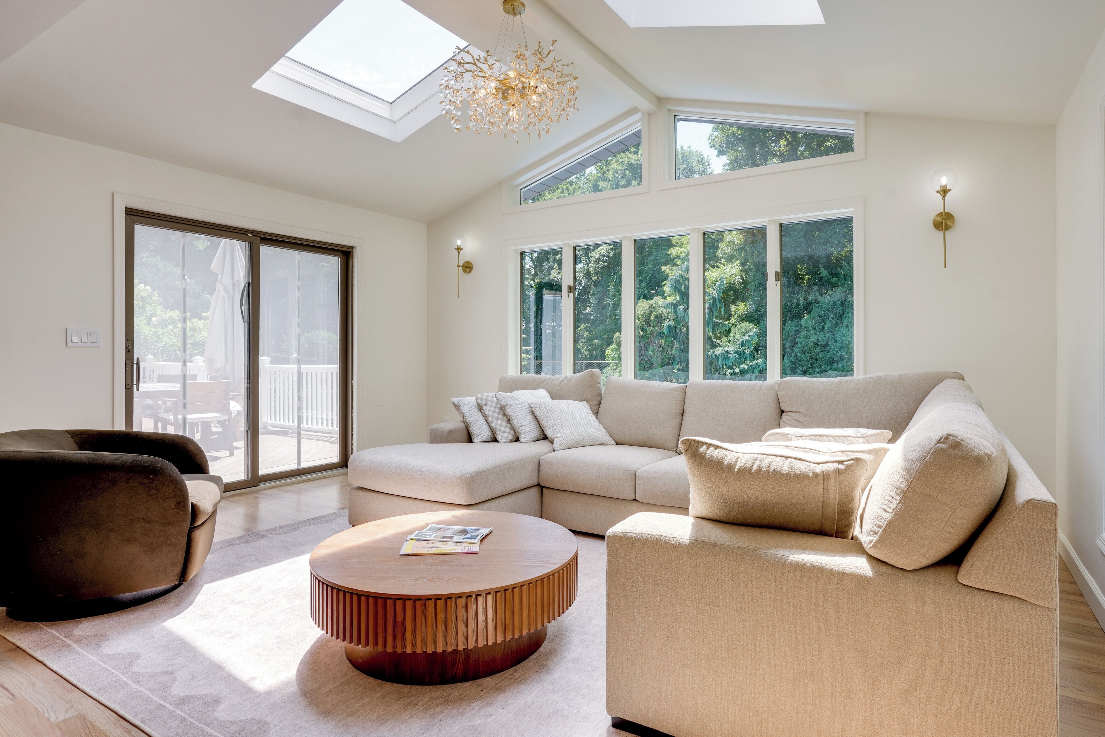 A spacious living room with a sectional sofa, a round coffee table, and a large sliding glass door leading to an outdoor area.