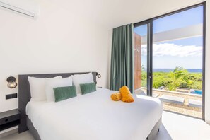 Habitació d'hotel amb un llit, vistes al mar i un balcó amb piscina.