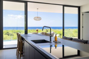 Eine moderne Küche mit einem großen Fenster und Blick auf eine Küstenlandschaft.