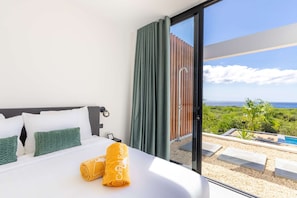 Habitació d'hotel amb llit, vistes a l'oceà i zona de piscina.