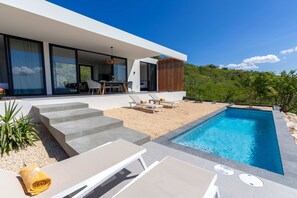 A modern house with a swimming pool, outdoor seating, and a view of the surrounding landscape. - Villa Terrazza sul Mare - Paradise at Coral Estate (St. Marie)