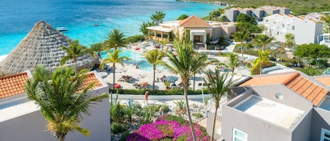 A resort with a pool area, palm trees, and ocean views.