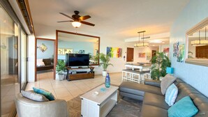 A modern living room with a television, sofa, coffee table, and a ceiling fan. - Wake Up to the Sea Oceanfront Retreat W207 (Puerto Peñasco)