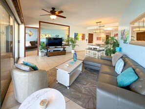 A modern living room with a television, sofa, coffee table, and a ceiling fan. - Wake Up to the Sea Oceanfront Retreat W207 (Puerto Peñasco)