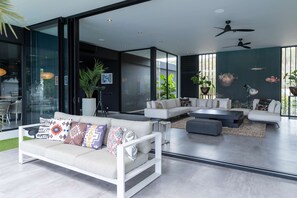 Ein modernes Wohnzimmer mit einer Eckcouch, einem Couchtisch und einem Deckenventilator.