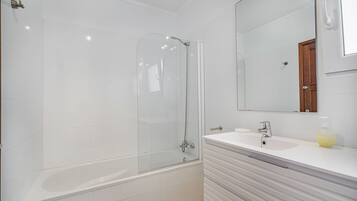 A modern bathroom with a glass-enclosed shower, a white sink, and a mirror above the vanity.