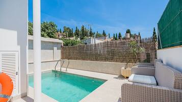 A rooftop pool area with a clear view of the surrounding landscape, including trees and buildings.