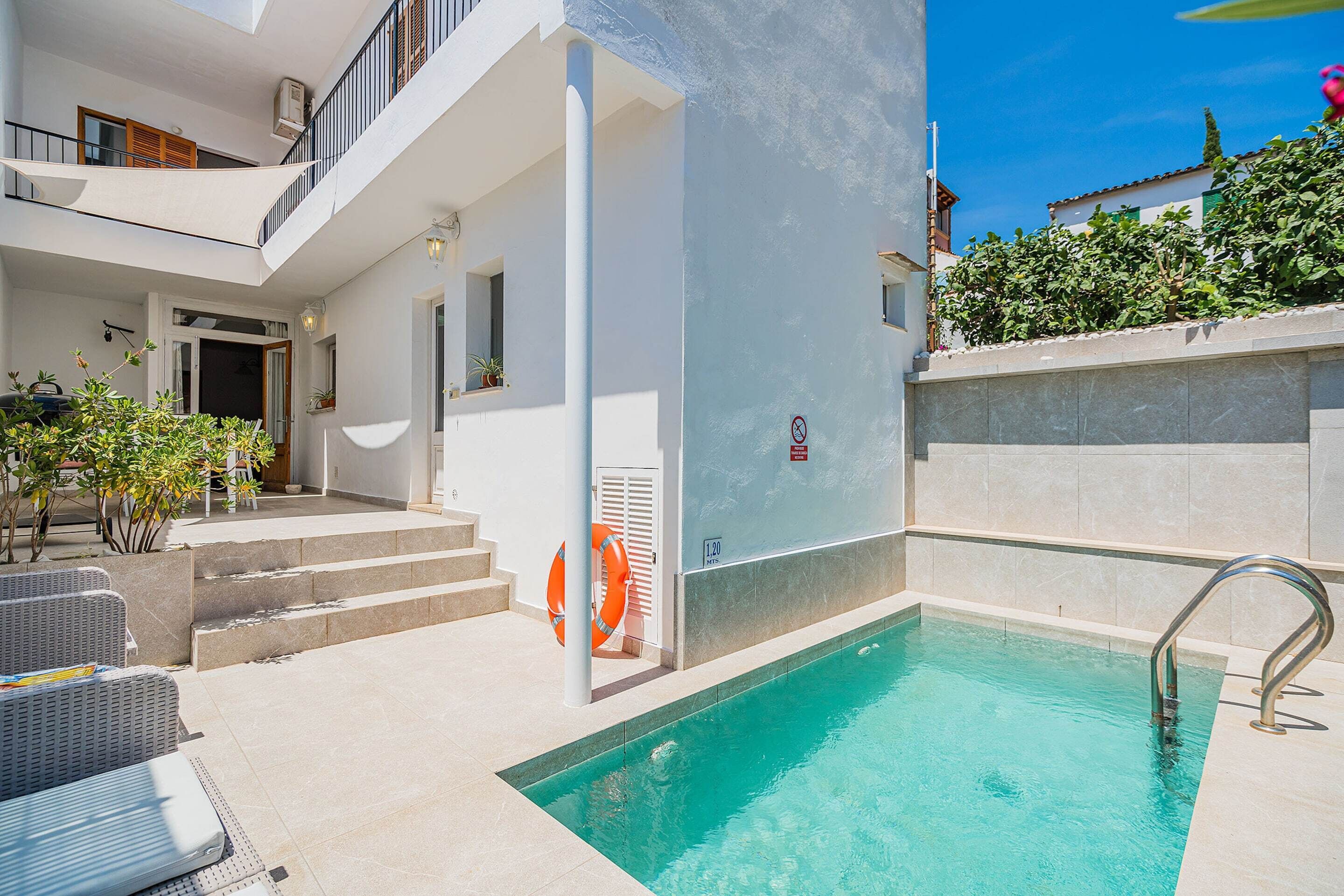 A modern building with a swimming pool, outdoor seating, and a staircase leading to the entrance.