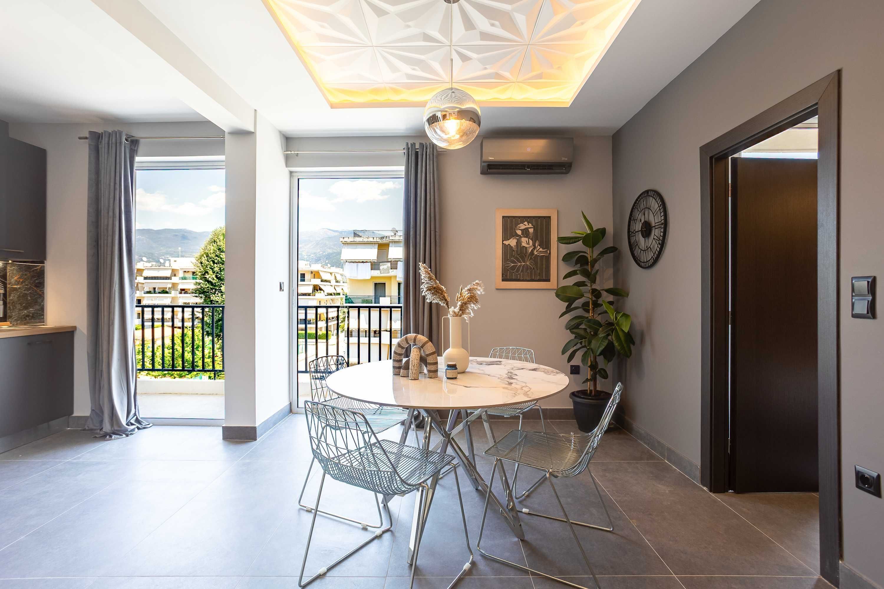 Un comedor moderno con una mesa redonda, sillas de metal, un jarrón decorativo y un reloj de pared.