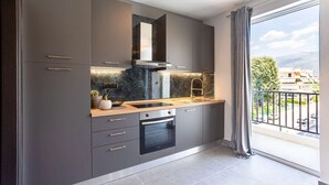 A modern kitchen with grey cabinets, a black oven, and a marble backsplash. - Socrates Suites Open City Views in Kalamata (Kalamata)