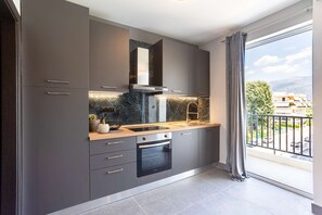 A modern kitchen with grey cabinets, a black oven, and a marble backsplash. - Socrates Suites Open City Views in Kalamata (Kalamata)