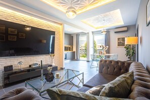 Ein modernes Wohnzimmer mit Fernseher, Glastisch und Ledersofa.