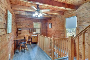 A wooden cabin interior with a dining area, a ceiling fan, and a staircase. - Classic New England Cabin on Belleau Lake (Wakefield)