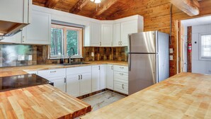 A kitchen with wooden cabinets, a stainless steel refrigerator, and a wooden countertop. - Classic New England Cabin on Belleau Lake (Wakefield)