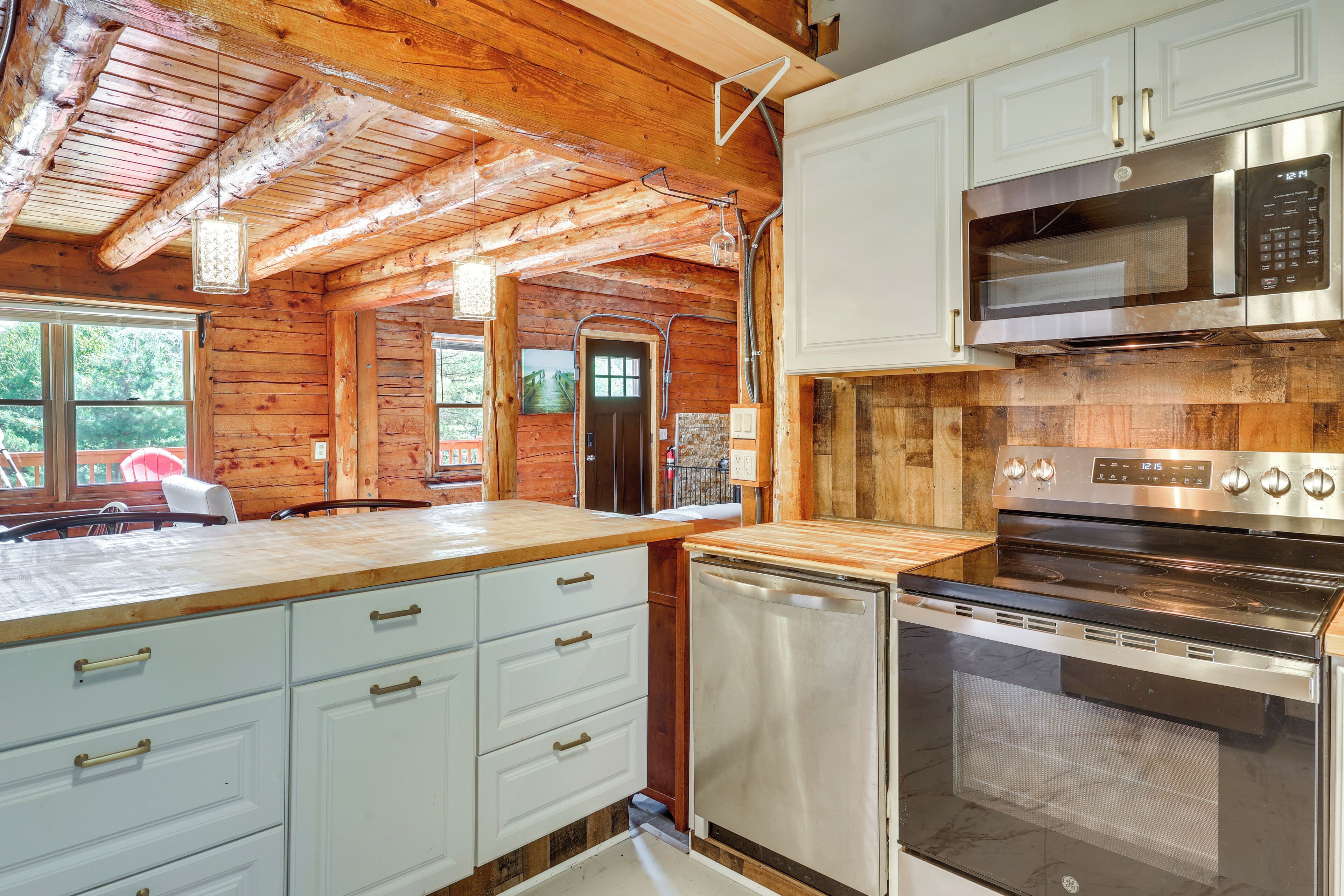 A kitchen with wooden beams, white cabinetry, a stainless steel microwave, and a built-in oven.