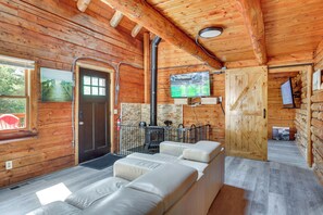L’intérieur d’une cabane en rondins, avec une cheminée, un téléviseur et un canapé.