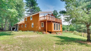 A two-story log cabin with a balcony, surrounded by trees. - Classic New England Cabin on Belleau Lake (Wakefield)