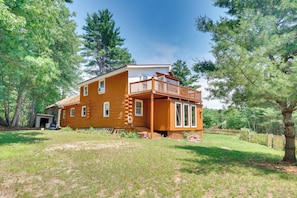 A two-story log cabin with a balcony, surrounded by trees. - Classic New England Cabin on Belleau Lake (Wakefield)
