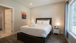 Un dormitorio con cama, mesita de noche, un reloj de pared y una ventana.