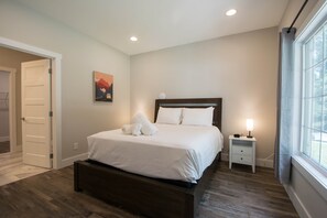A bedroom with a bed, a nightstand, a wall clock, and a window. - Modern Upper Retreat II 2 Suites Free Tix (Hendersonville)