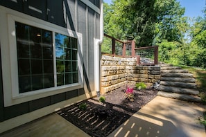 A house with a stone retaining wall, a wooden deck, and a window with a grid pattern. - Druid Hills Retreat II Sleeps 8 Free Tix (Hendersonville)