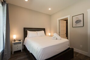 A neatly arranged hotel room with a bed, bedside tables, a lamp, and a framed picture on the wall. - Druid Hills Retreat II Sleeps 8 Free Tix (Hendersonville)