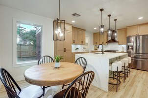 Una cocina moderna con una isla central, iluminación colgante y electrodomésticos de acero inoxidable.
