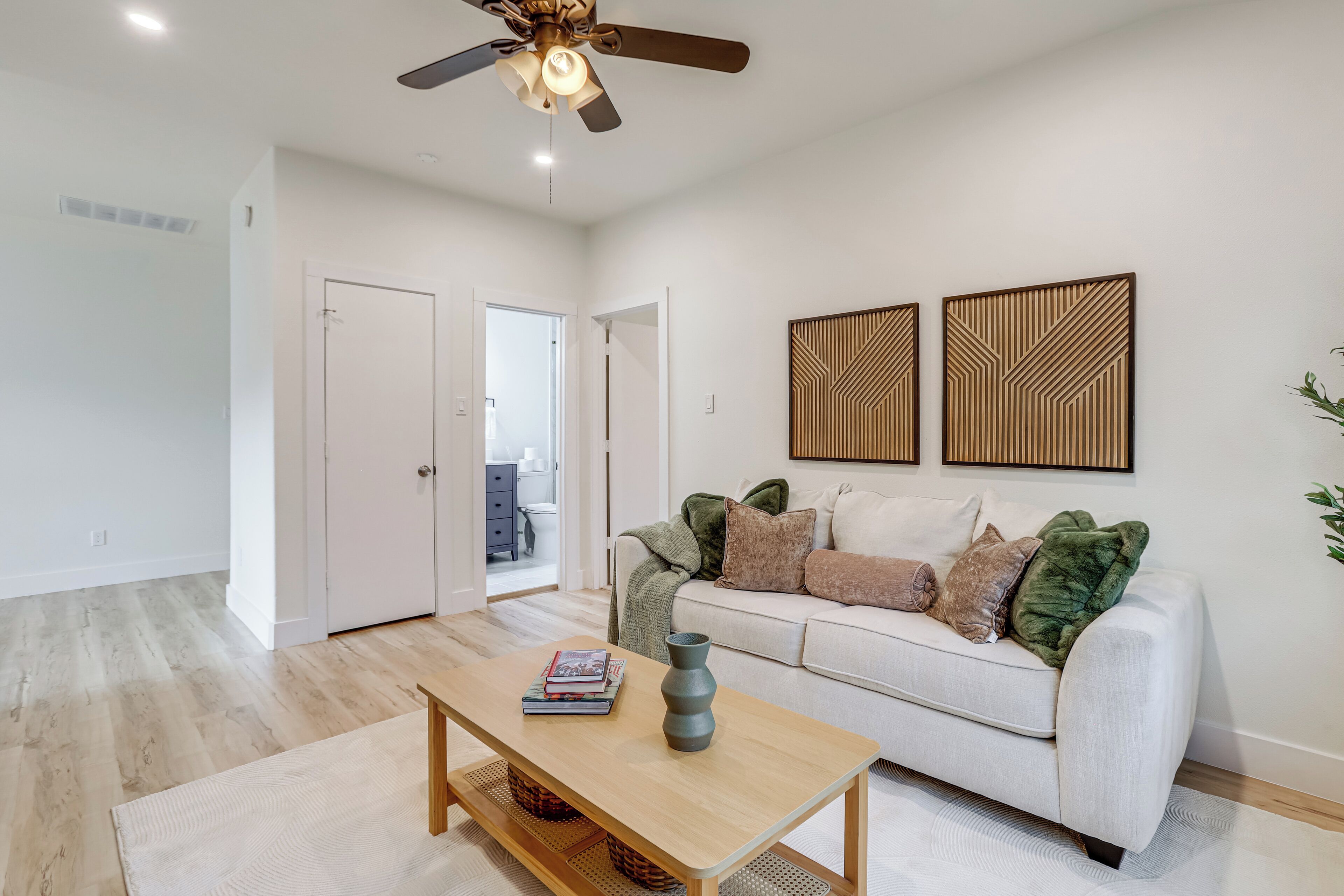A modern living room with a white sofa, a wooden coffee table, and a ceiling fan.