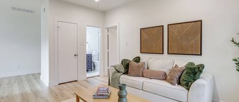 A modern living room with a white sofa, a wooden coffee table, and a ceiling fan.
