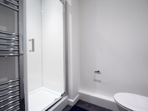 Ein Badezimmer mit Duschkabine aus Glas, einer weißen Toilette und einem Handtuchhalter.