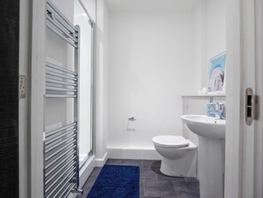 A bathroom with a white toilet, a sink with a blue patterned faucet, and a shower area. - Student Only The Paper Works (Sheffield)