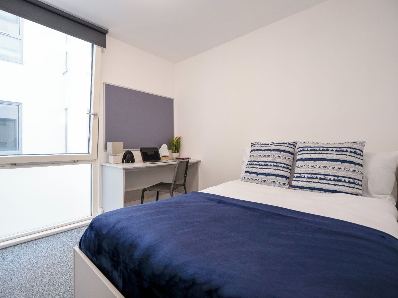 A bedroom with a bed, a desk, and a chair.
