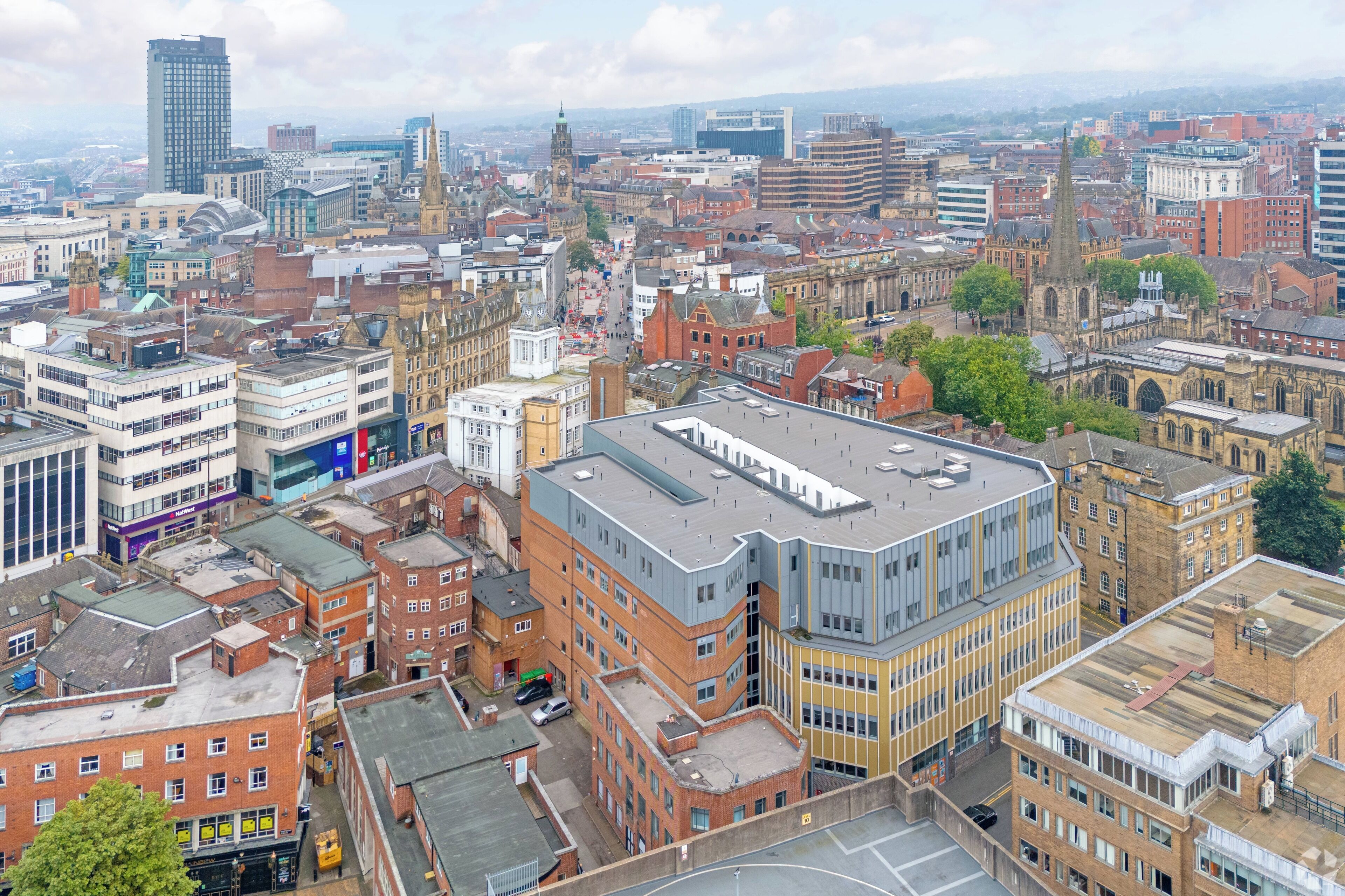 A cityscape with a mix of modern and historic buildings, including a prominent clock tower.