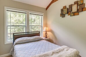 Une chambre à coucher avec un lit, une table de chevet, une lampe et une fenêtre avec des stores.